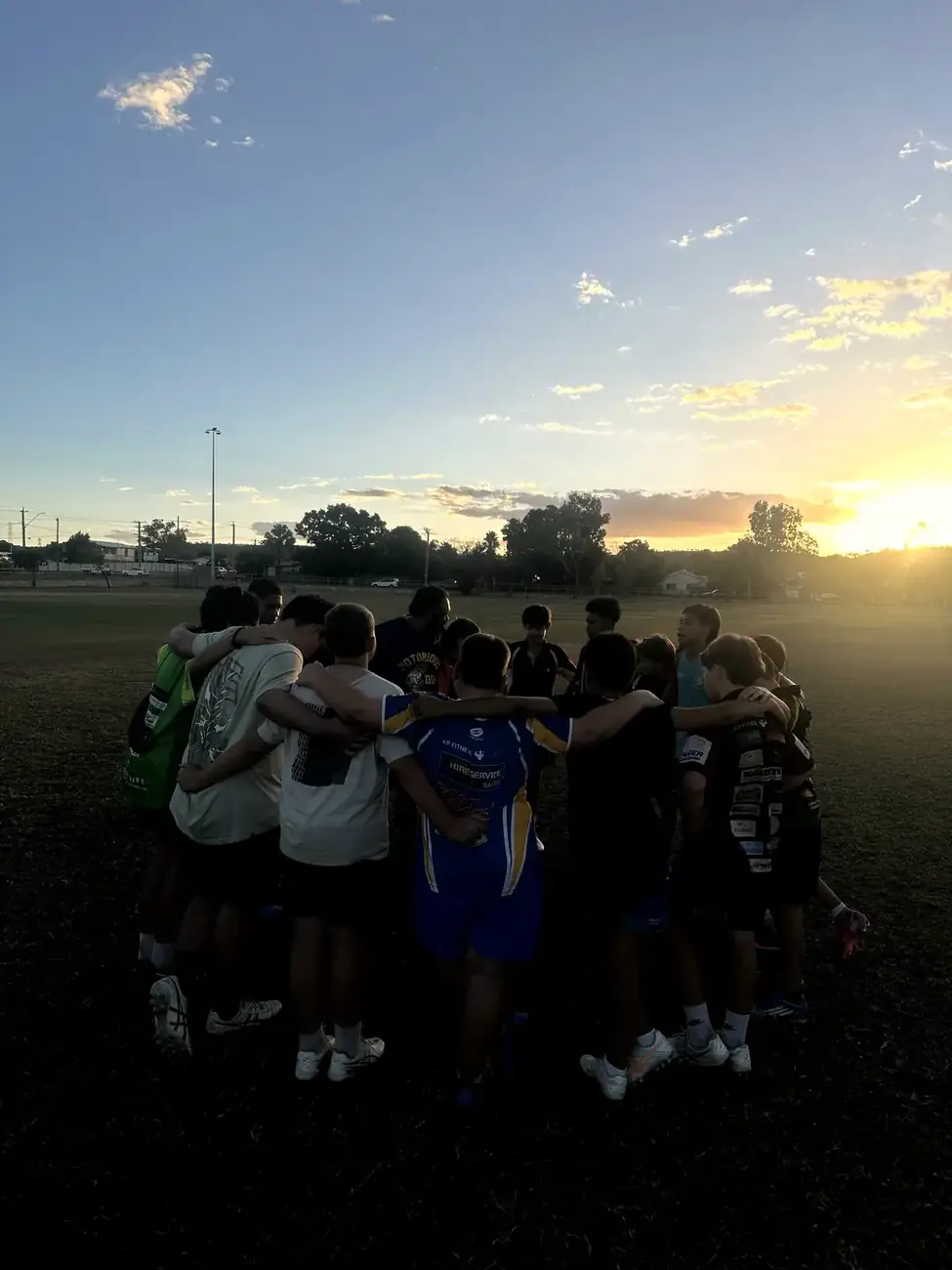 The team in a huddle at training as the sun goes down