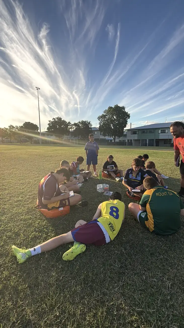 Players writing in their journals in a circle on the field