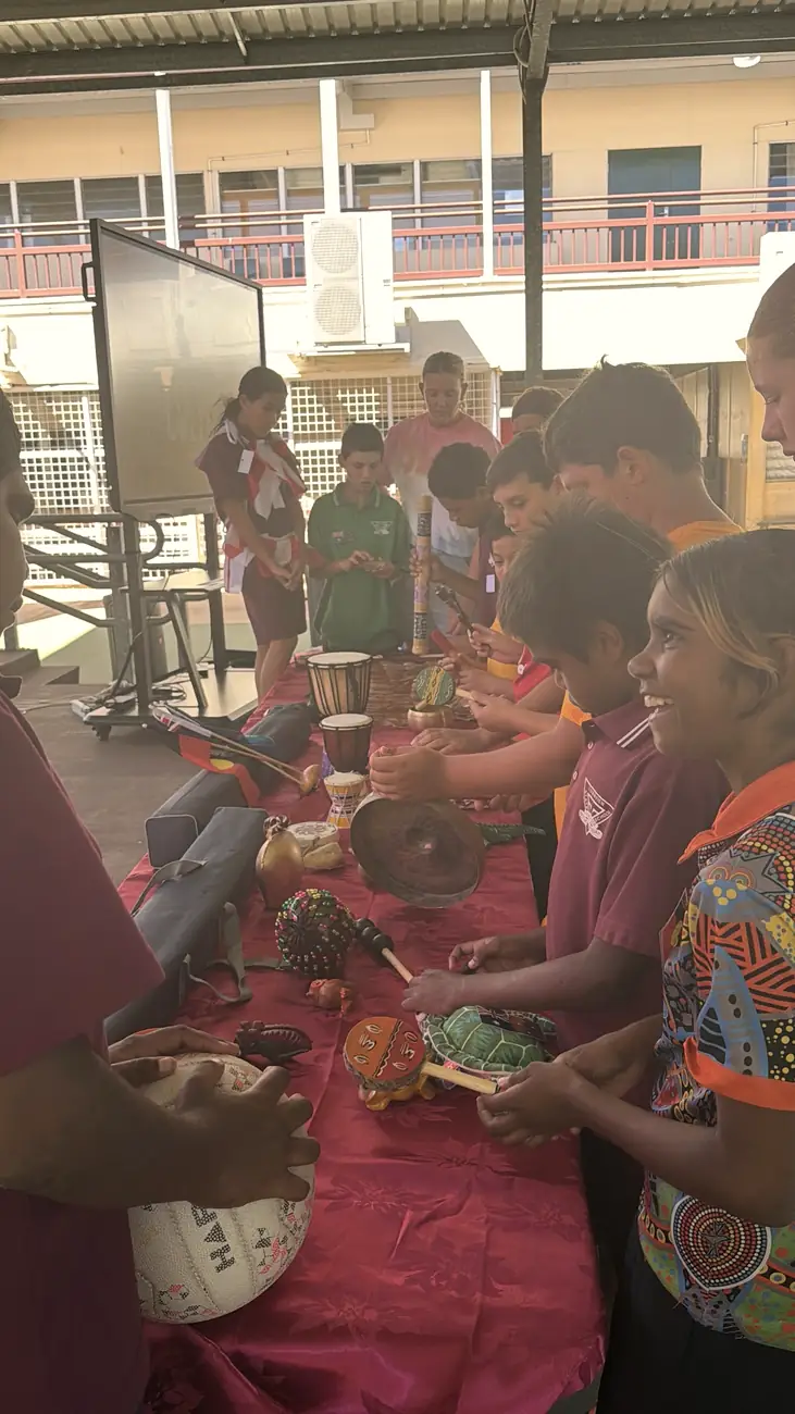 Students smiling as they try traditional instruments at a culture session