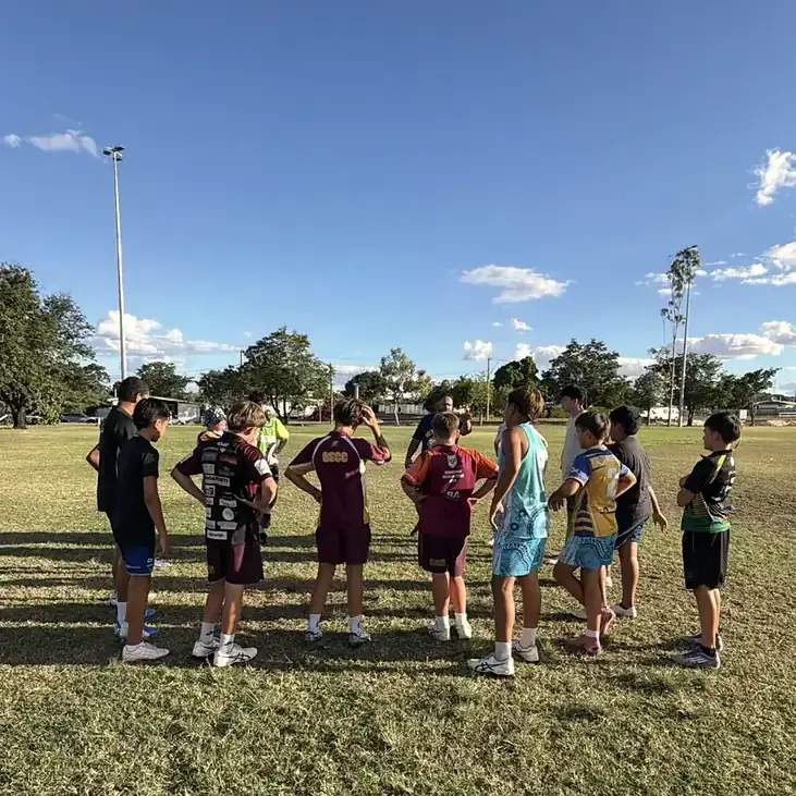 A coach talking with a group of young players on the field
